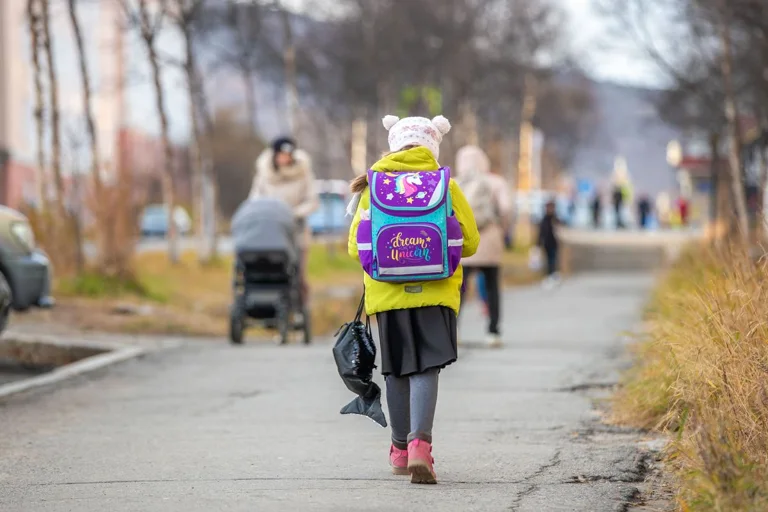 A child walking along a path with a colourful school backpack
