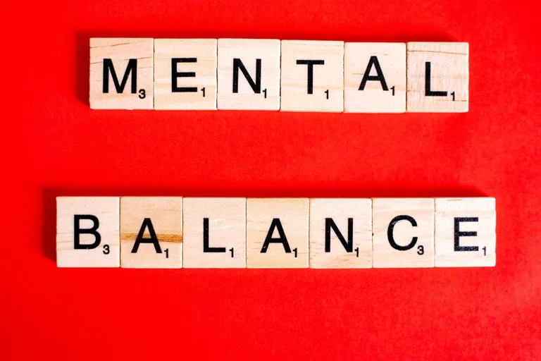 Wooden letter blocks spelling Mental Balance on a red background